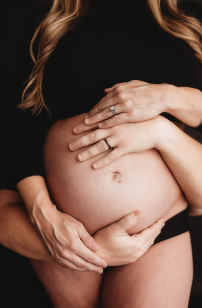 Expectant parents embrace pregnant belly during studio Maternity Photoshoot in Charleston, SC.