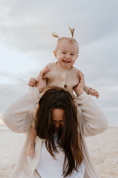 Photo of a baby on their mums shoulders smiling
