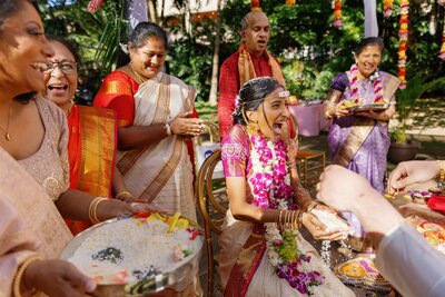 A newlywed laughing as they hold rice during a wedding tradition 