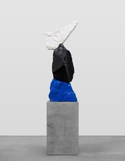 An artistic sculpture featuring blue, black, and white stones stacked vertically