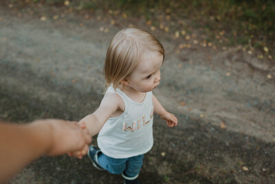 2 year old child is walking and holding her parent's hand in Finland