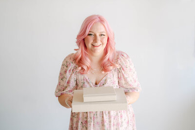 Photo of Brittney Lear holding two cream heirloom albums, an Indianapolis maternity Photographer