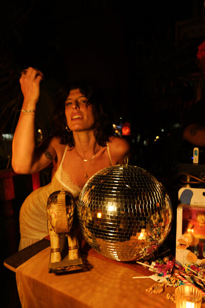 Tristan Thibodeau with disco ball, bathed in amber light, embracing the wild feminine.