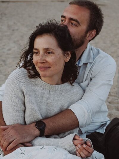 A loving couple hugging on the beach. This represents a couple in the aftermath of infidelity feeling relieved after remorse for an affair was expressed properly. If you have been unfaithful and feel remorse you can benefit from our expert guidance through the Remorse Blueprint E-course to show you exactly how to express remorse and start healing.