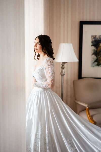 bride wearing white wedding gown while looking out of window