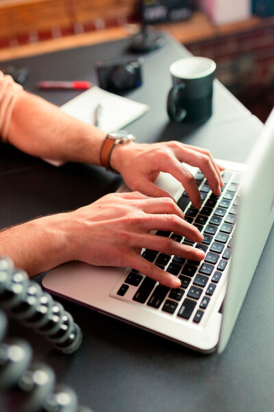 Expert working on a laptop in her office, managing monthly Google Ads campaigns. The black desk features a coffee cup, highlighting a professional setting for top Google Ads management services.