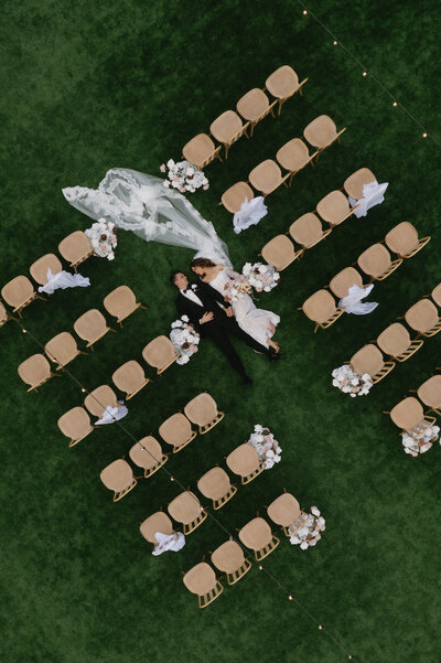 Couple lays down in aisle for drone photo at Gather Estate Wedding