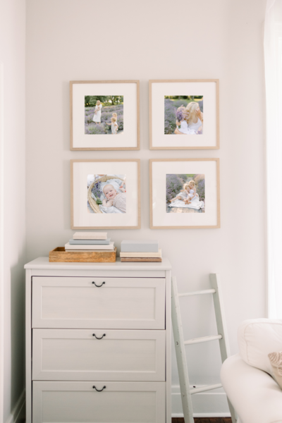 A photo of a room with a light colored dresser and four framed photos on the wall