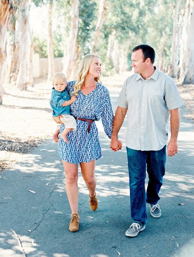 A family holds hands while walking through a park during their family portrait session with Camarillo photographer Daniele Rose