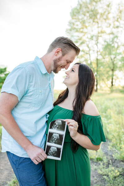 couple outside showing off their  ultrasound photo strip