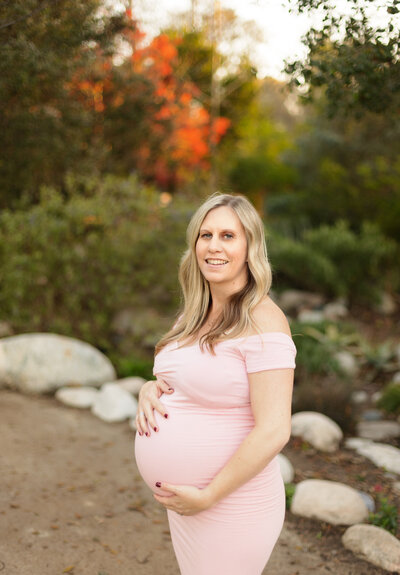 Pregnant woman posing in park wearing pink dress photographed by maternity photographer Candice Berman Photography