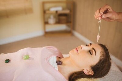 A client receiving a Reiki session with chakra crystals and a pendulum at BioSalud Integrative Therapy Center, showcasing energy balancing and holistic healing practices.