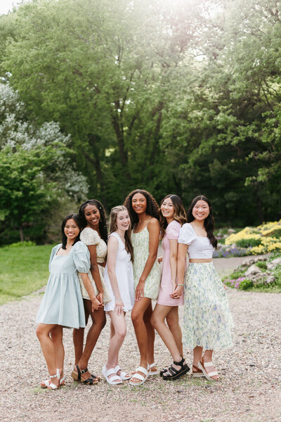 Group of senior girls outside in floral dresses posing close to each other