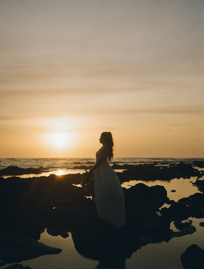 Silhouette of bride ride on the rocks of a beach in Mexico