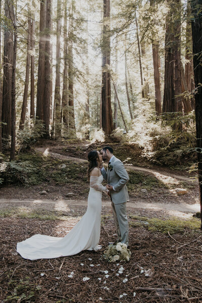 Bride and groom share their first kiss as a married couple at their Big sur elopement in the redwoods surrounded by trees