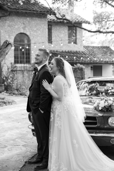 An Austin-based wedding photographer captures a bride and groom standing next to a classic car at their special day.