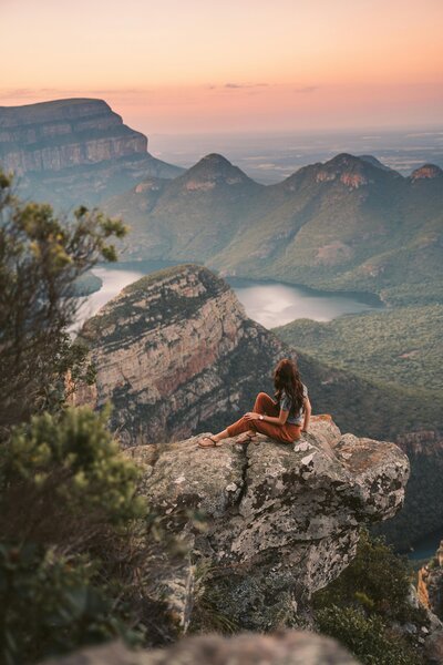 Woman sitting on a cliff watching the sunset