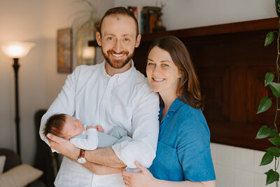 Couple looking at camera while holding newborn son, during photo session  by St. Louis photographer Jacoby Andrick