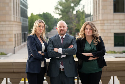 three attorneys in business suits with arms crossed on balcony of wyoming state capitol building in cheyenne