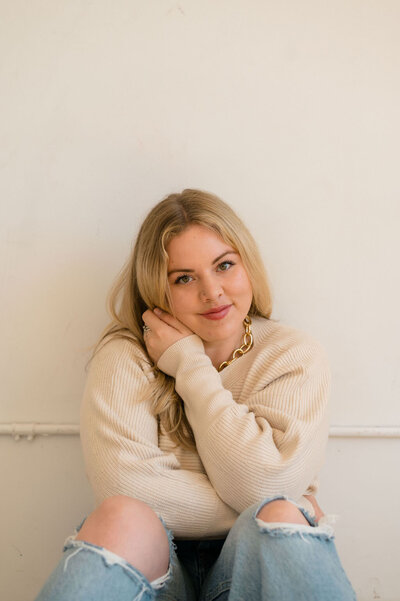 woman sitting with her knees bent and her hand resting on the opposite cheek of her face