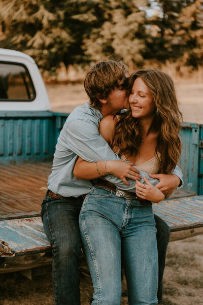 Cowboy and cowgirl sharing a kiss beside vintage truck on a Northern California ranch