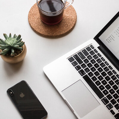 Desk with a laptop, phone, coffee, and succulent plant.