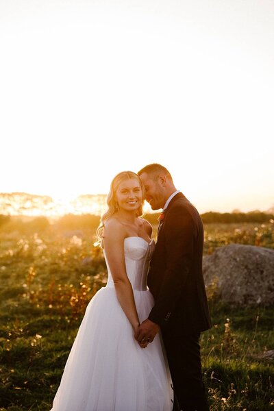 natasha and shaun holding hands while the sun sets behind them at goodin country gardens, photographed by taranaki wedding photographer aimee kelly