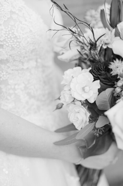 B&W image taken by Virginia Wedding Photographer, Rachael Mattio of a bridal bouquet next to a wedding dress.
