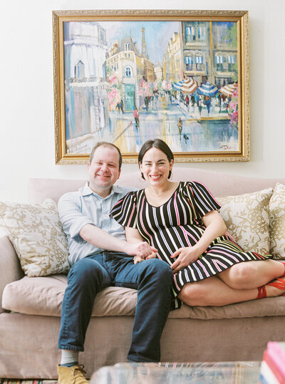 husband and pregnant wife embracing on a couch