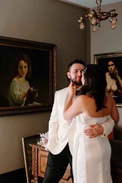 A wedding couple with their arms around each other about to kiss 