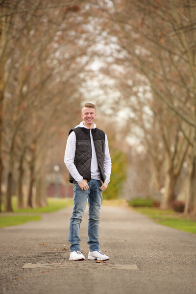 Senior boy on tree lined path at Julia Davis Park in Boise, ID.