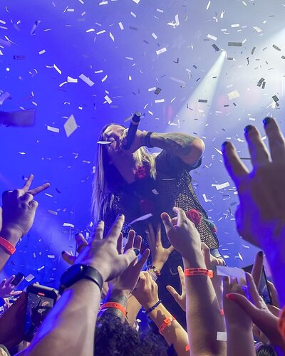 Photo taken from audience during concert of musician singing with confetti in the air