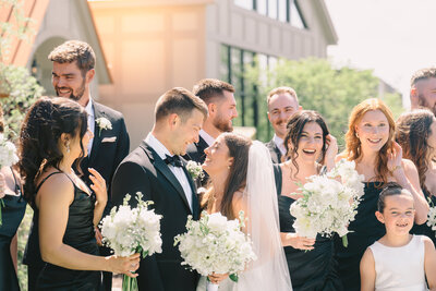 A bride and groom laugh and have fun with their wedding during golden hour outside of a manor in Grand Rapids.