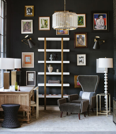 Modern decorated room with black wall, gallery wall frames, gray chair, and tall white shelf