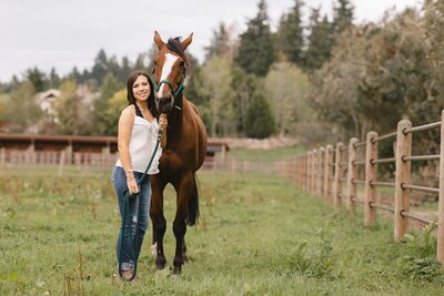Young woman standing with her horse at a barn in Redmond.