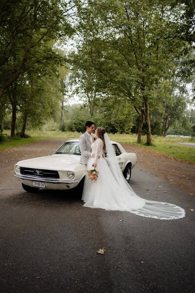 Getrouwd koppel met vintage auto in het bos, vastgelegd door trouwfotograaf Julia de Groot uit Utrecht en Veenendaal