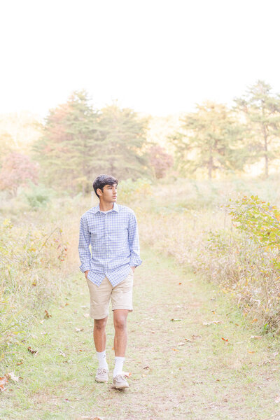 boy walking in a field during Fairfax County, VA senior pictures