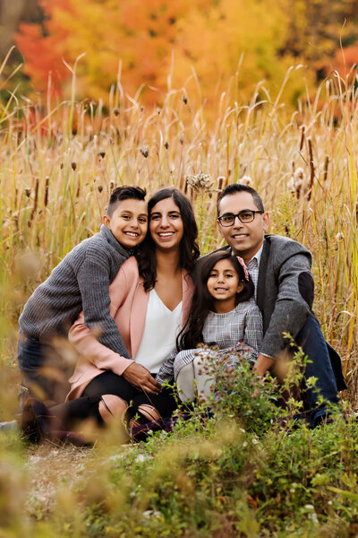 Mom and dad sitting on the ground with their son and daughter for the fall family photography session in Burlington, Ontario.