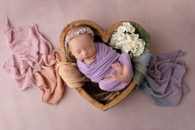 sleeping newborn swaddled in purple baby wrap in portrait studio