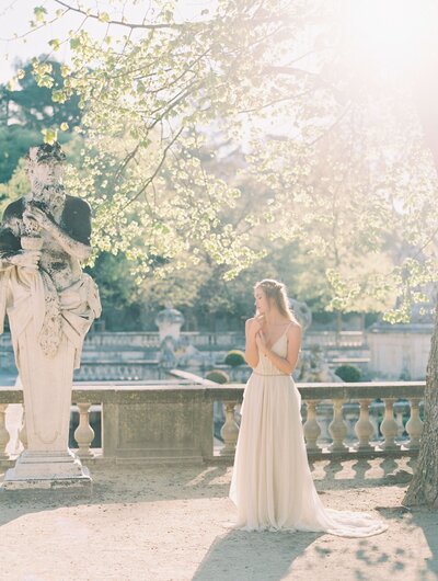 Bride standing in a garden with a statue in San Diego