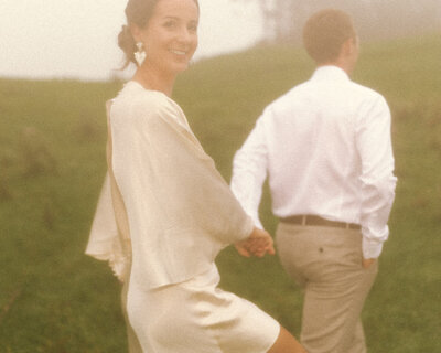A vintage wedding portrait of a couple holding hands in a grassy field. Captured by Eilish Burt Photography