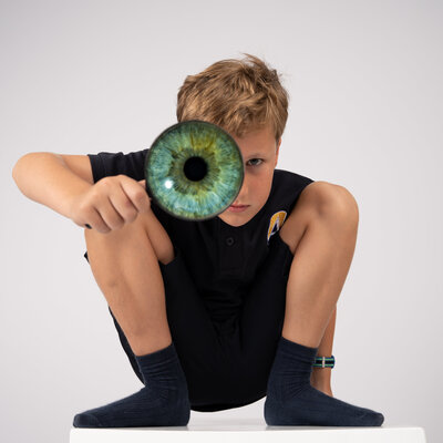 School boy with macro photo of  green iris