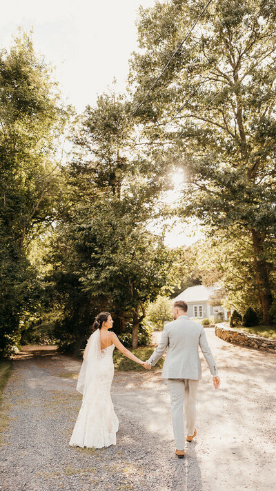 Capture the Romance: Newlyweds Holding Hands in Beautiful Green Setting on a Sunlit Day