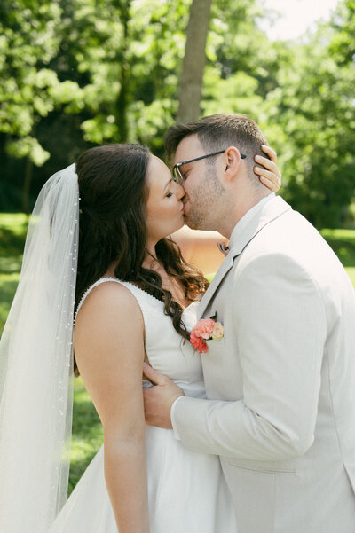 A couple bride and groom embraces in a kiss to the head during their wedding day