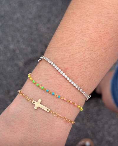 Gold permanent bracelet stack featuring a cross charm, from Jazzy's Glam Bar.