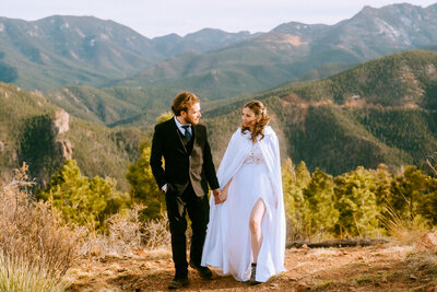Bride and groom rest on rock during their Colorado elopement in front of Pikes Peak