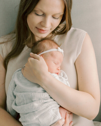 mother cuddles newborn daughter on her chest during an in home newborn session