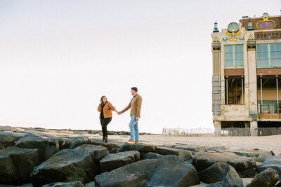 Engagement session on beack rocks, couple holding hands