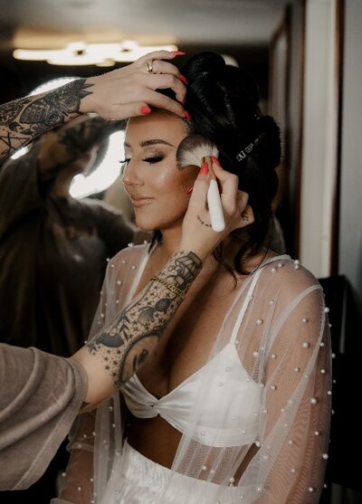 Person sitting down as someone does their makeup.