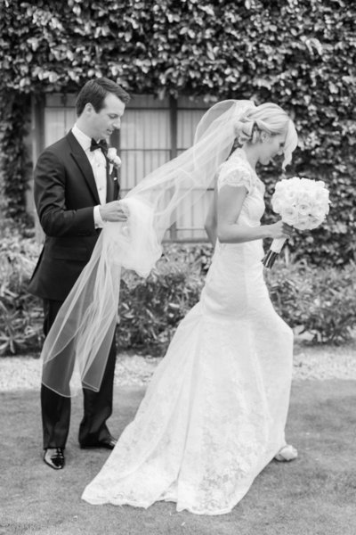 Romantic wedding photography capturing a heartfelt moment as the groom carries his bride’s veil while walking together in an Arizona wedding.